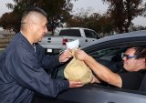 Kings County Supervisor Richard Valle helps distribute turkeys during Operation Gobble Turkey Giveaway Monday afternoon in Hanford's Home Garden area.